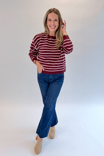 Front view of woman wearing Swagger Boutique’s Burgundy &amp; Pink Striped Sweater with jeans against white studio background.