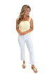 Front view of woman wearing Swagger Boutique’s Butter Yellow Peplum Tank with jeans against white studio background.