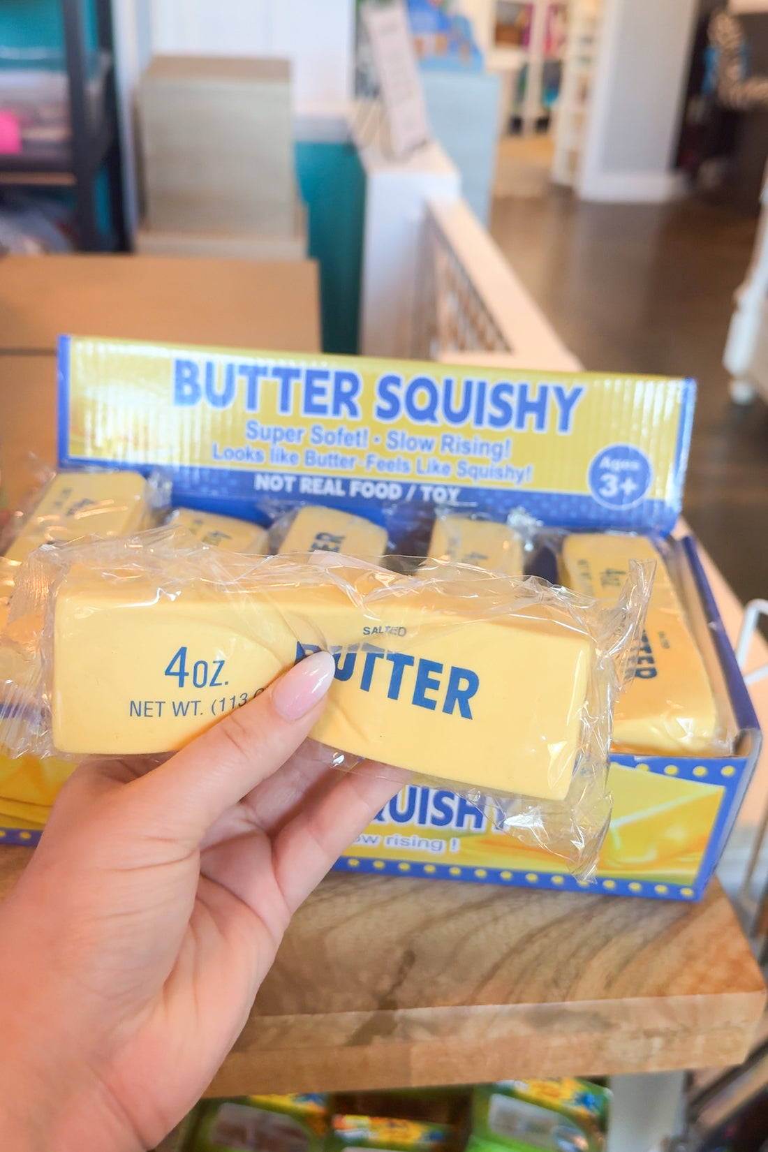 Butter Squishy toy held by a hand with packaging in the background