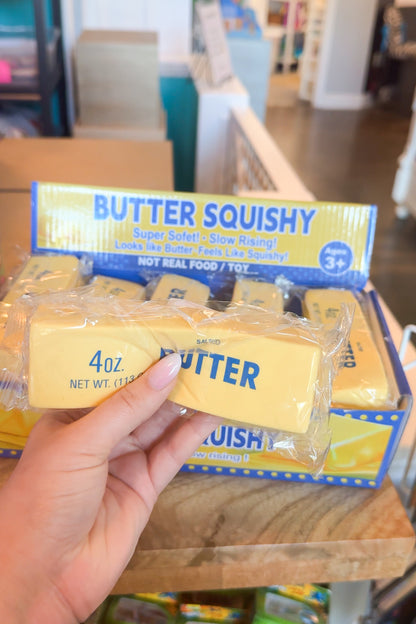 Butter Squishy toy held by a hand with packaging in the background