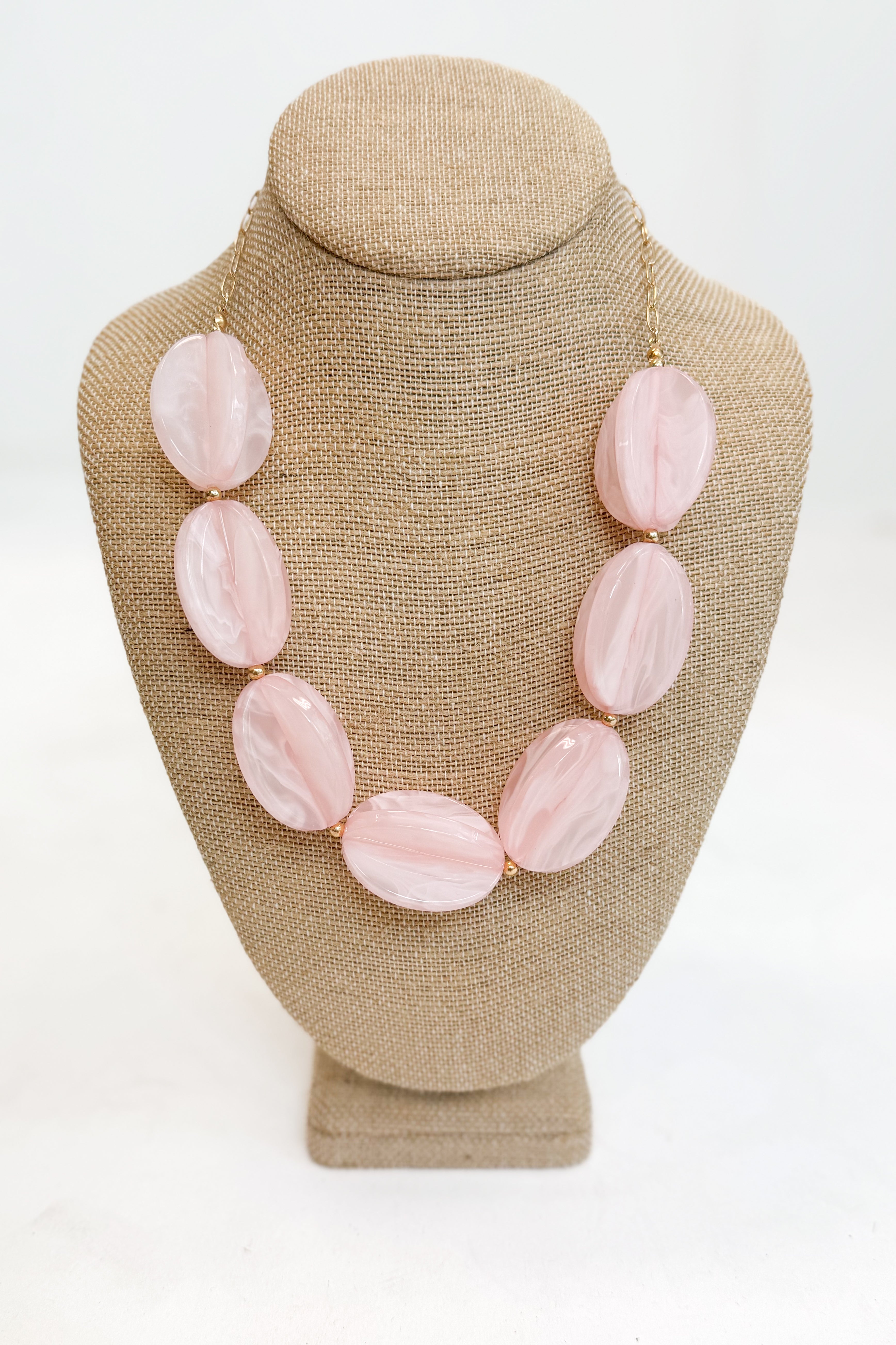 Necklace with pink oval stones on a beige mannequin bust against a white background