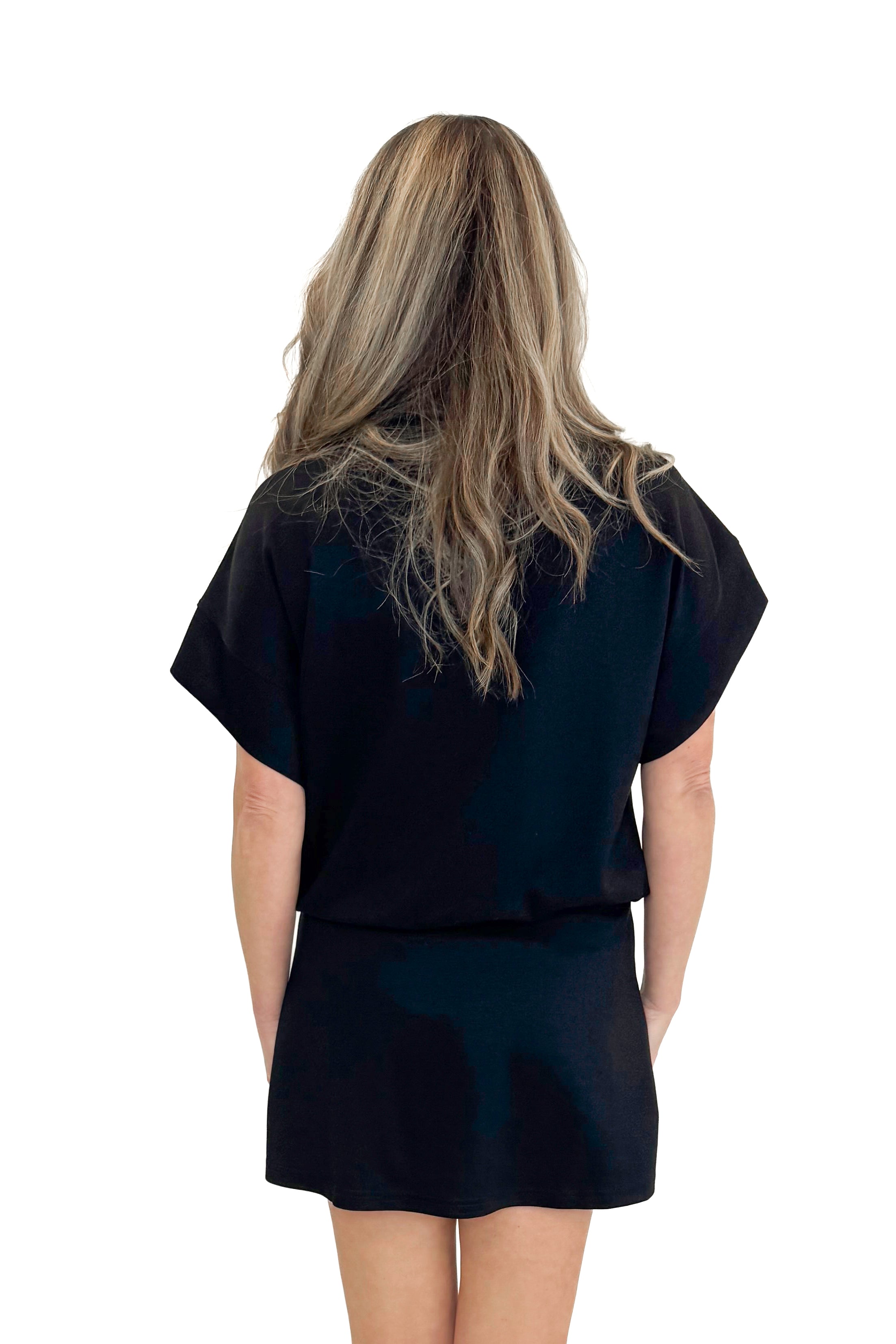 Back view of woman wearing Black Athleisure Skirt with matching sweatshirt against white studio background.