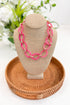 Necklace on a mannequin bust with a woven tray and floral background