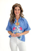 Front view of woman wearing Blue Floral Embroidered Top with jeans against white studio background.