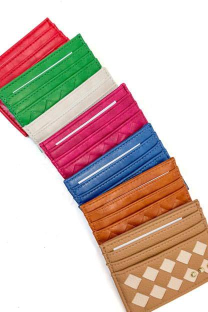 A set of slim bifold cardholder wallets in multiple colors, arranged diagonally on a white background. The wallets feature quilted and checkered patterns in red, green, cream, magenta, blue, tan, and brown
