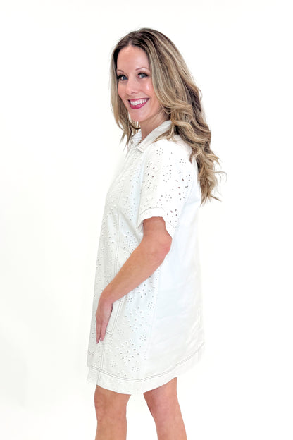 Side view of woman wearing Cream Eyelet Pocket Detail Dress with sandals against white studio background.