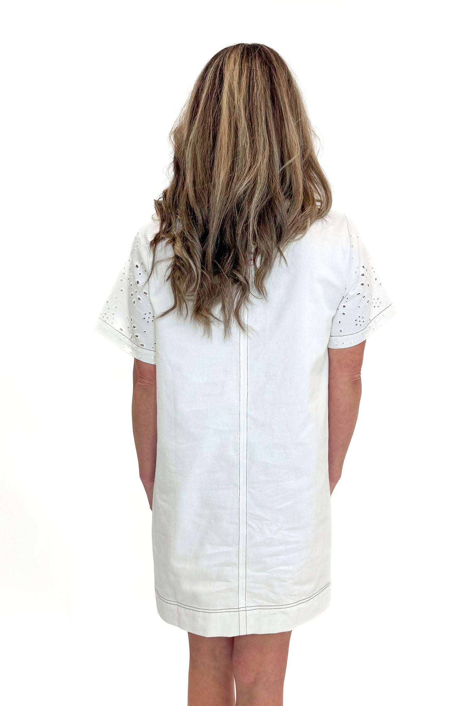 Back view of woman wearing Cream Eyelet Pocket Detail Dress with sandals against white studio background.