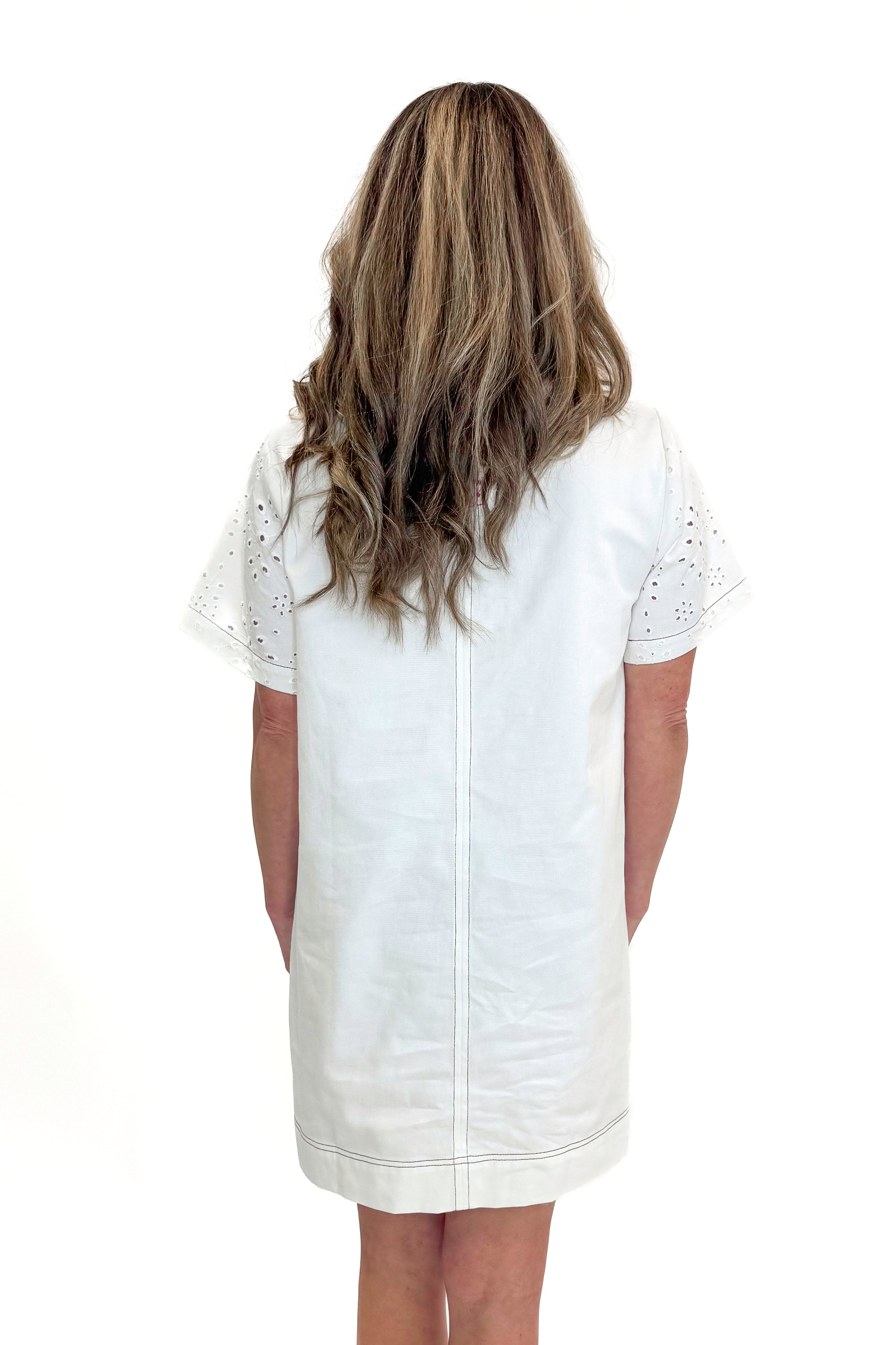 Back view of woman wearing Cream Eyelet Pocket Detail Dress with sandals against white studio background.