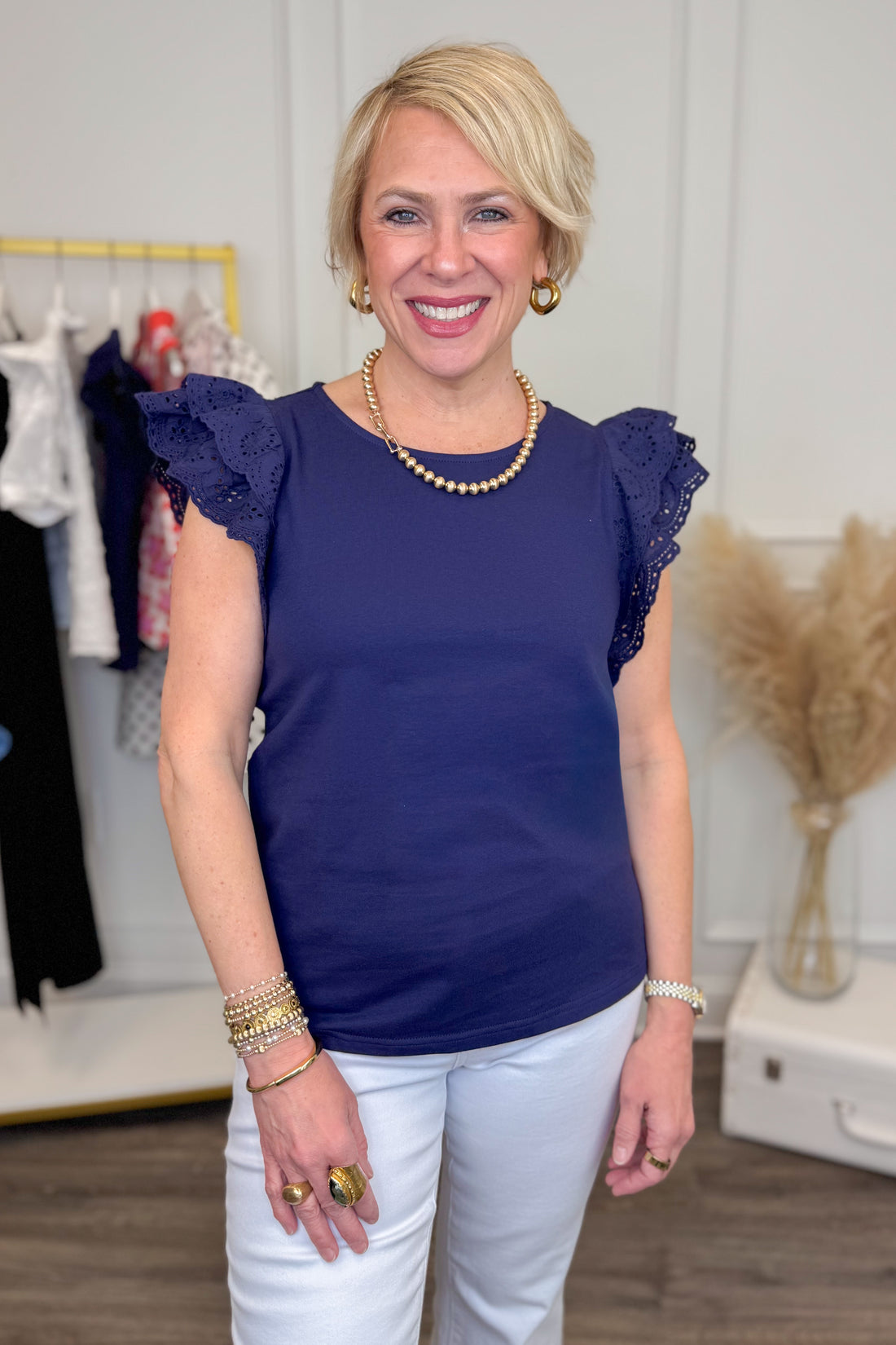 Woman wearing a navy blue top with ruffled sleeves in a clothing store.