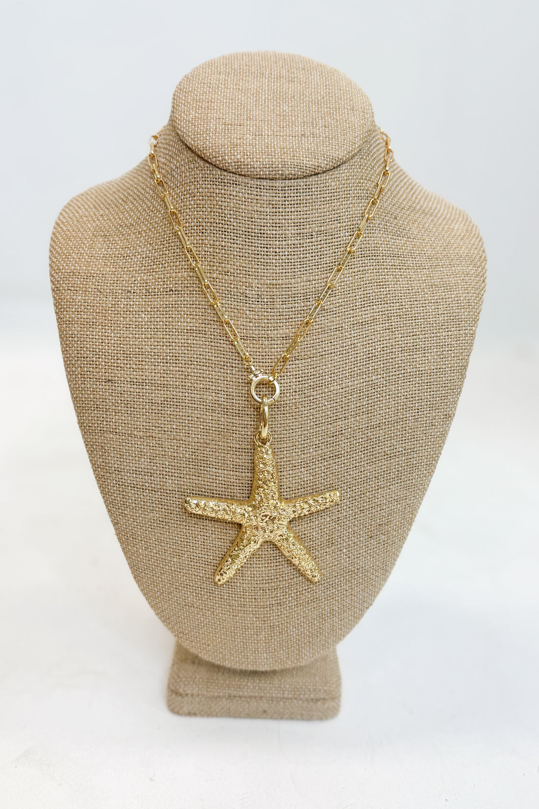 Gold starfish pendant necklace on a mannequin bust with a white background