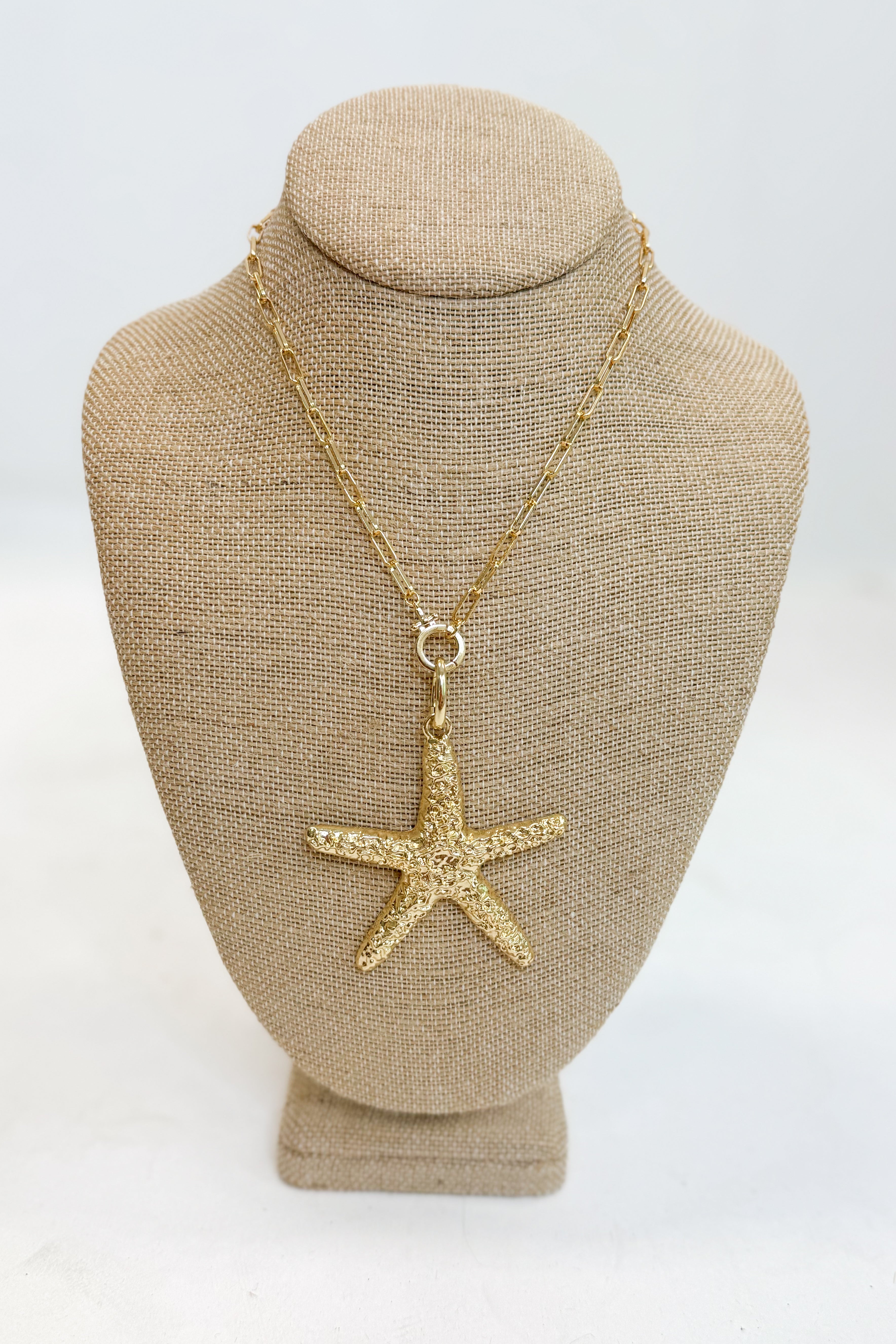Gold starfish pendant necklace on a mannequin bust with a white background