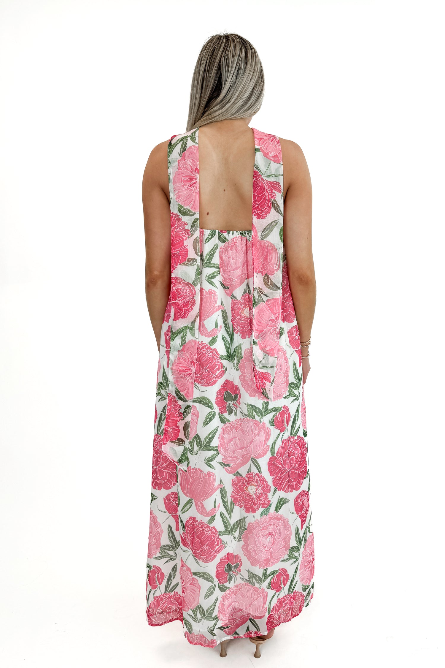 Back view of woman wearing Pink Floral Maxi Dress With Convertible Scarf against white studio background.