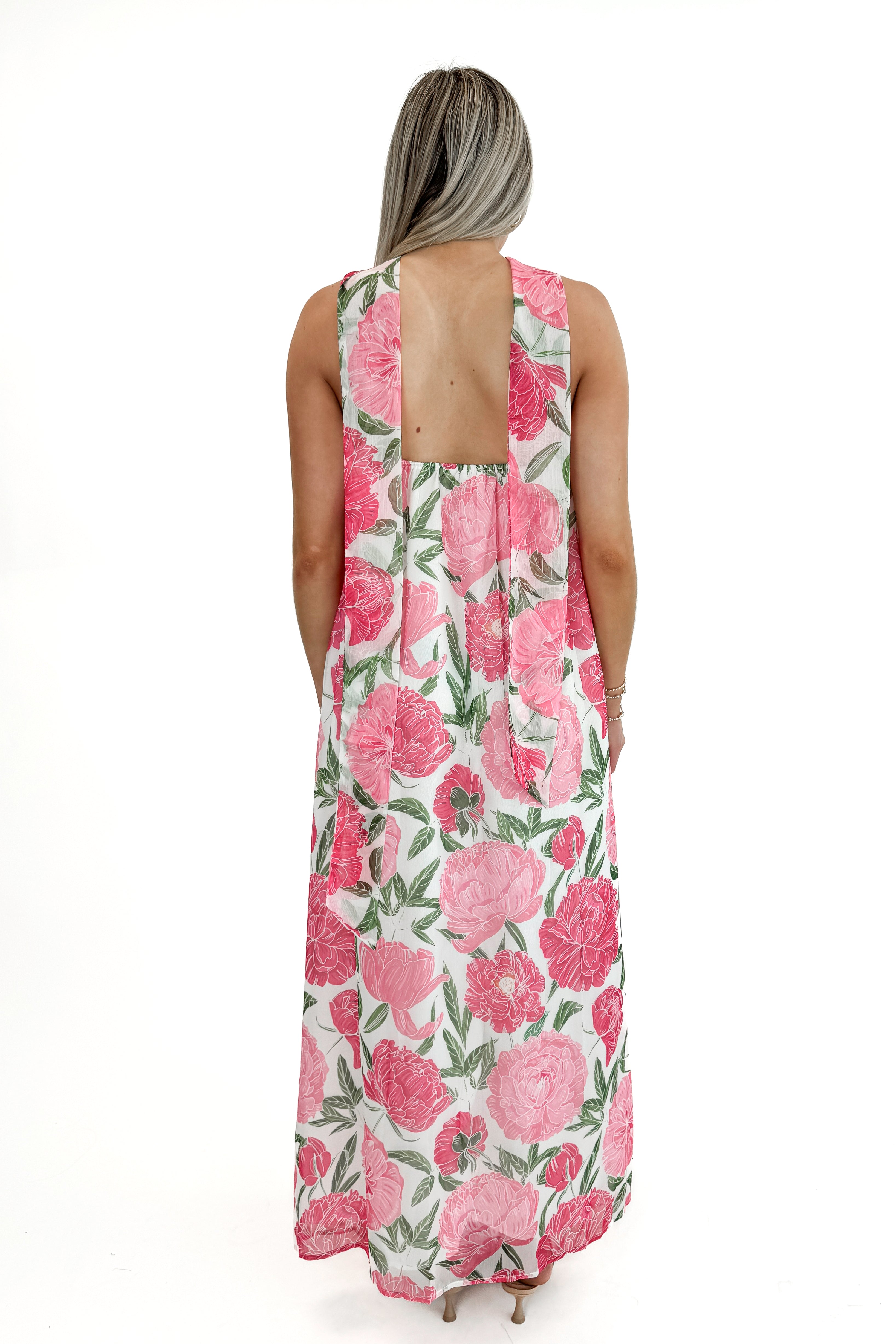 Back view of woman wearing Pink Floral Maxi Dress With Convertible Scarf against white studio background.