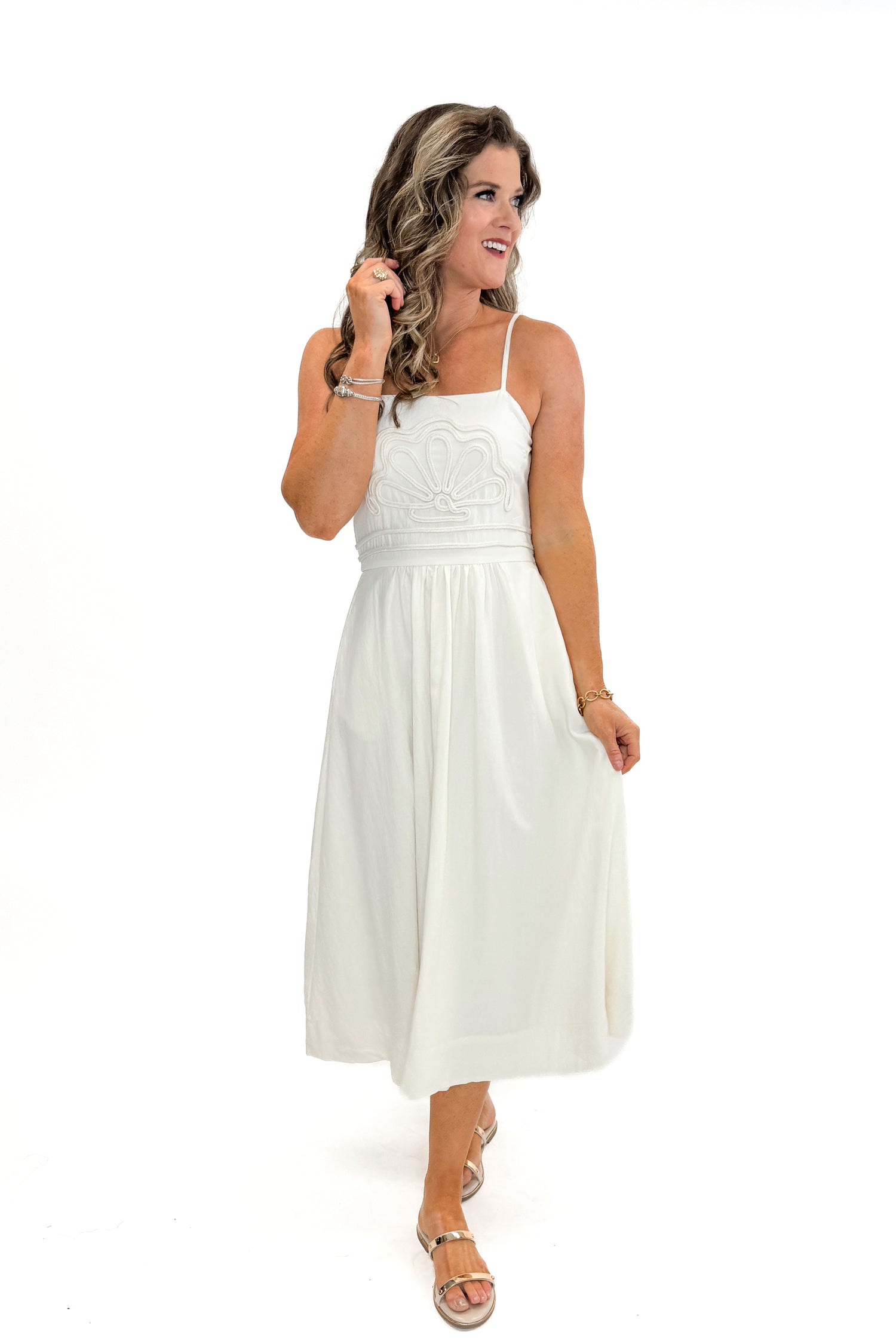 Front view of woman wearing Cream Shell Embroidered Midi Dress by TCEC with gold bar sandals against white studio background.