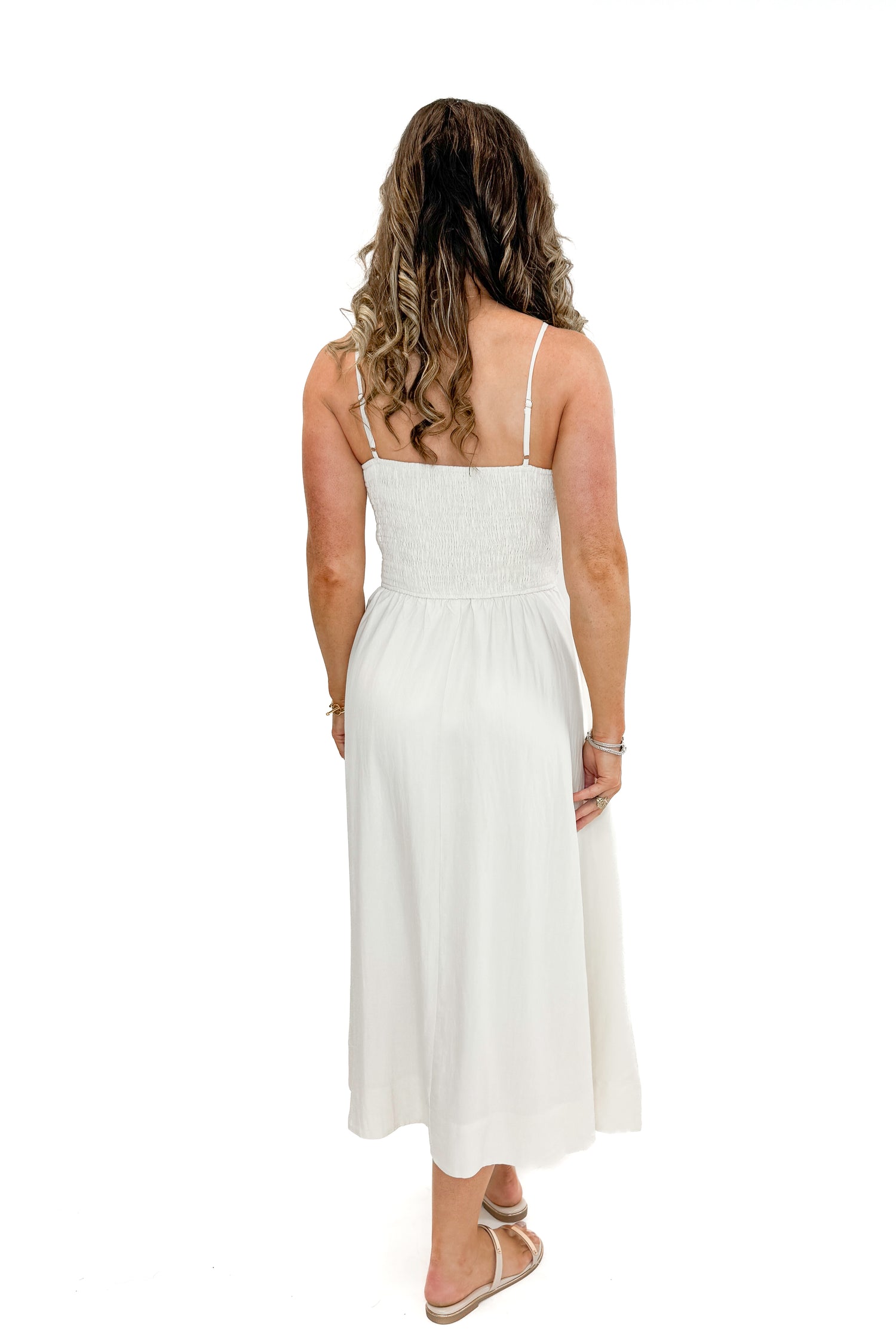 Back view of woman wearing Cream Shell Embroidered Midi Dress by TCEC with gold bar sandals against white studio background.
