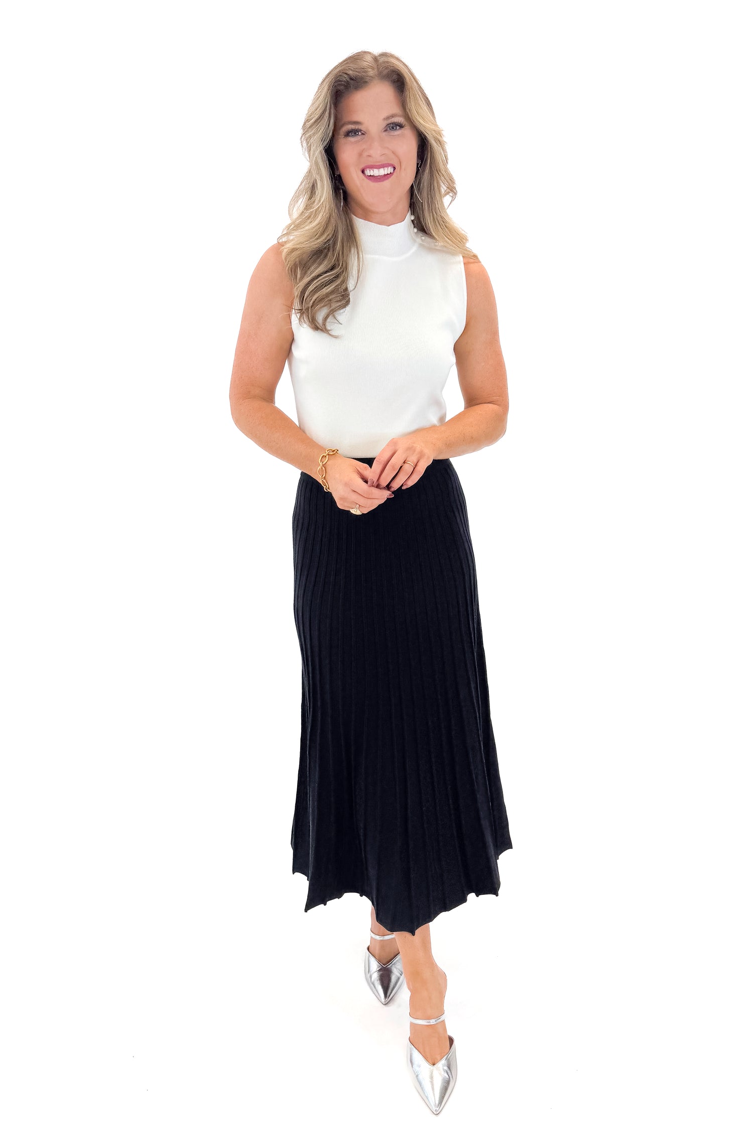 Front view of woman wearing Off White Pearl Detail Mock Neck Top with Black Pleated Sweater Skirt against white studio background.