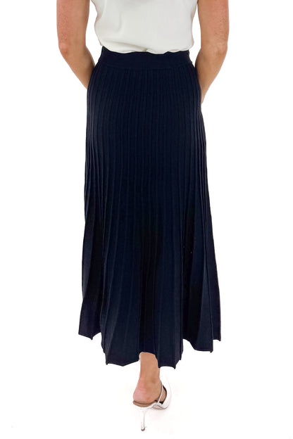 Back view of woman wearing Off White Pearl Detail Mock Neck Top with Black Pleated Sweater Skirt against white studio background.