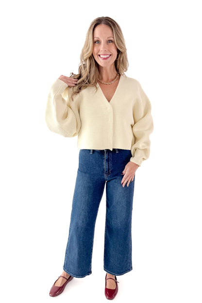 Front view of woman wearing Ivory Ribbed V-neck Cardigan with jeans against white studio background.