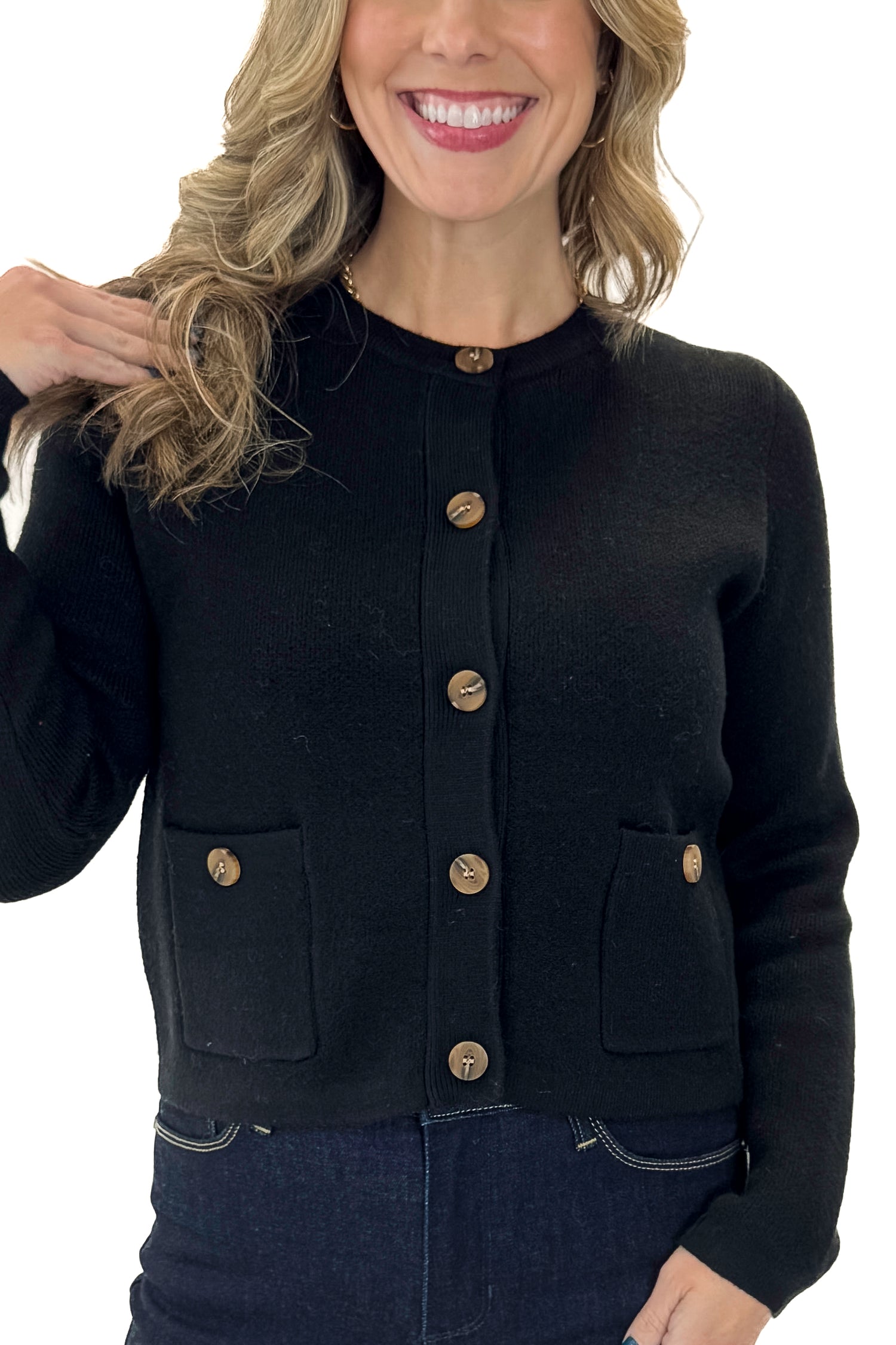Front detail view of woman wearing Black Button Detail Cardigan with jeans against white studio background.