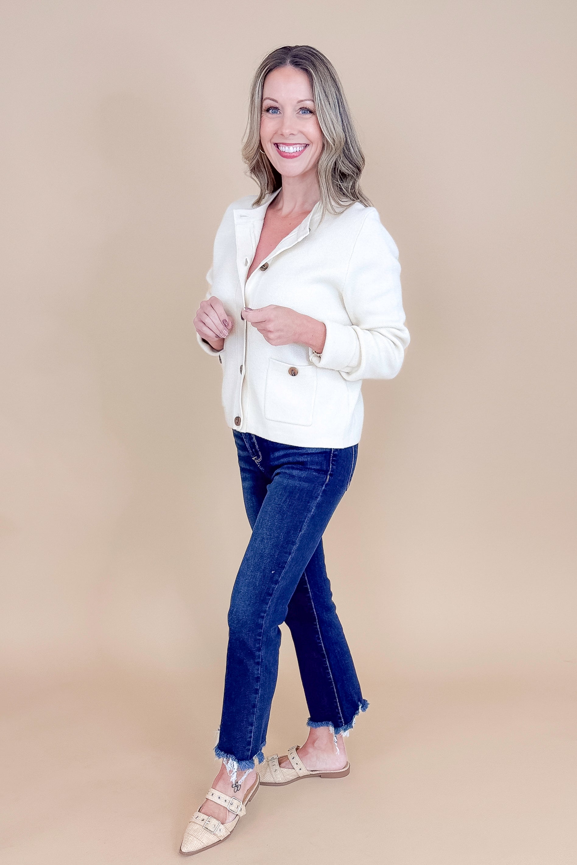 Side view of woman wearing Oatmeal Button Detail Cardigan with jeans against tan studio background.