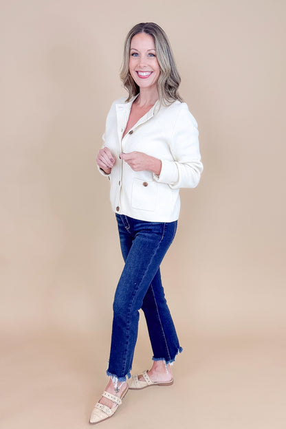 Side view of woman wearing Oatmeal Button Detail Cardigan with jeans against tan studio background.