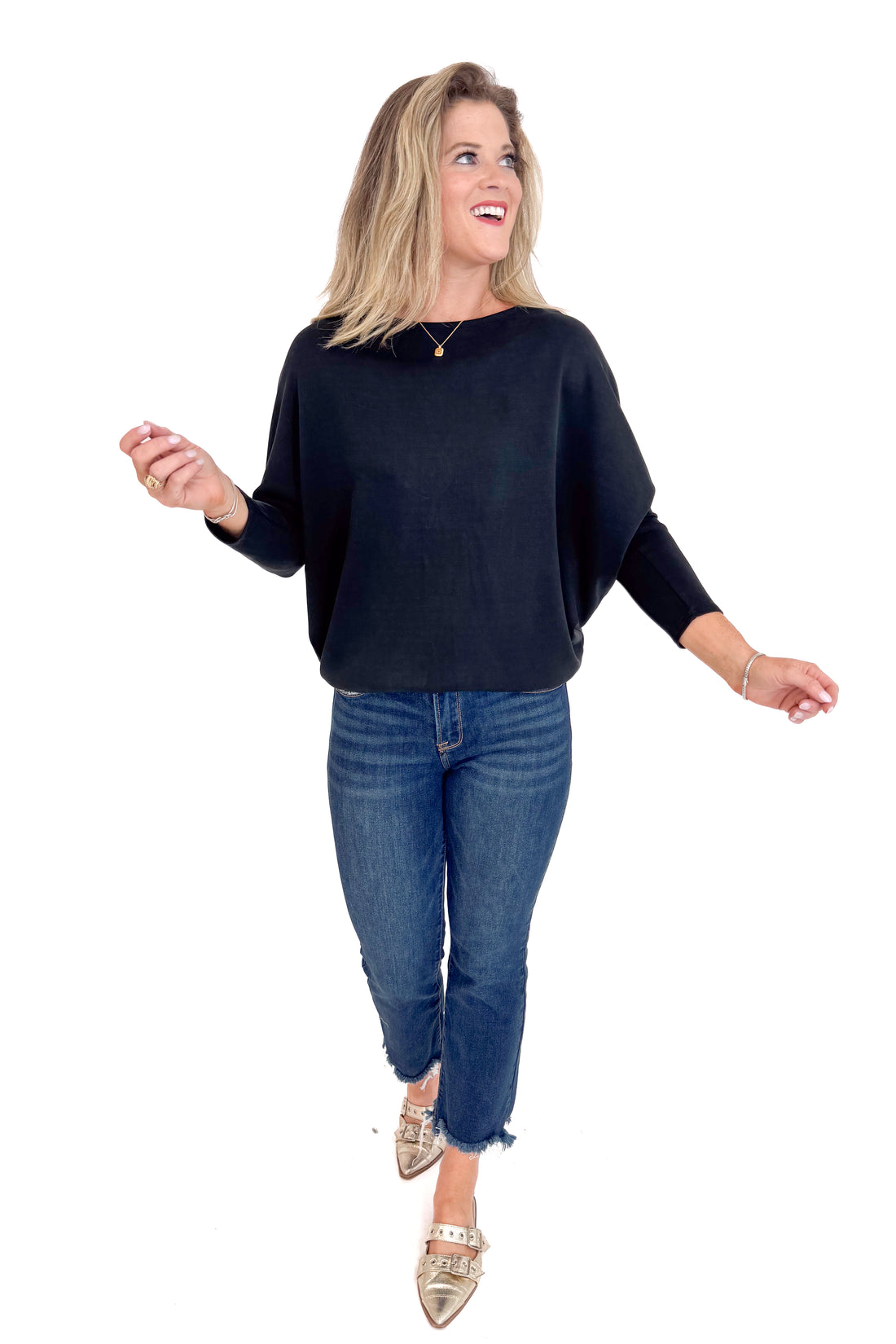 Woman wearing a black sweater and blue jeans on a white background