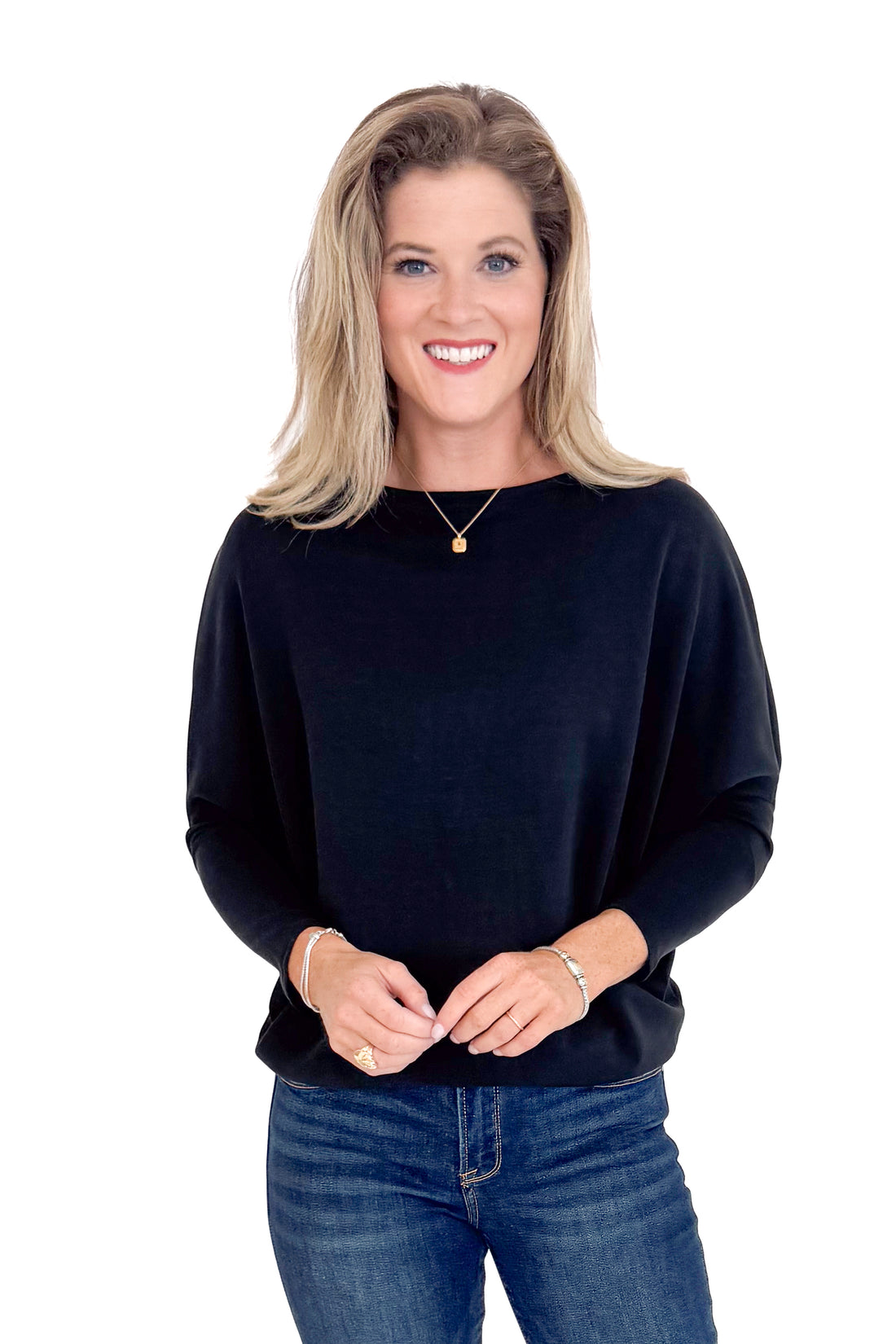 Woman wearing a black sweater and blue jeans on a white background