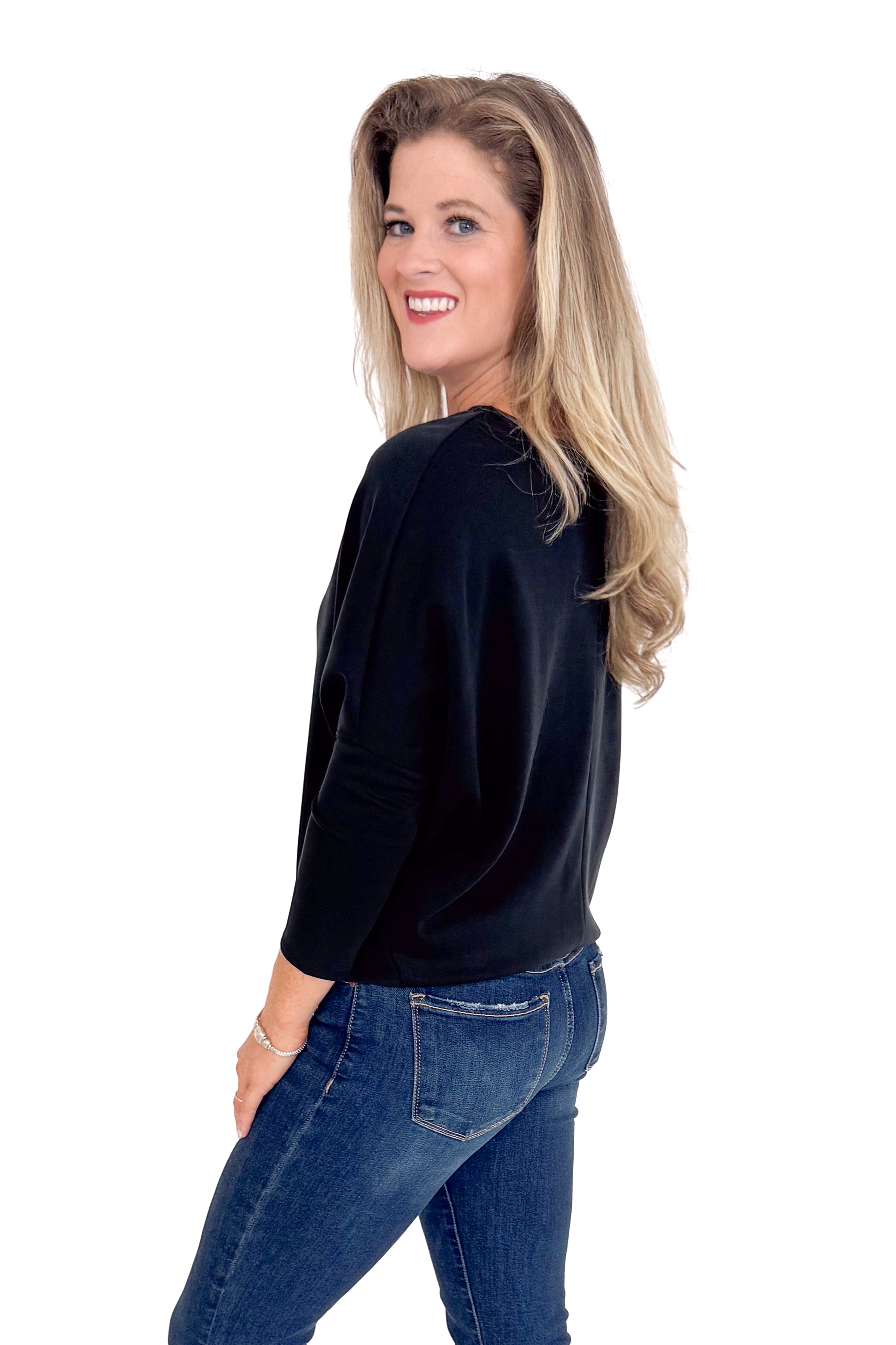 Woman wearing a black sweater and blue jeans on a white background