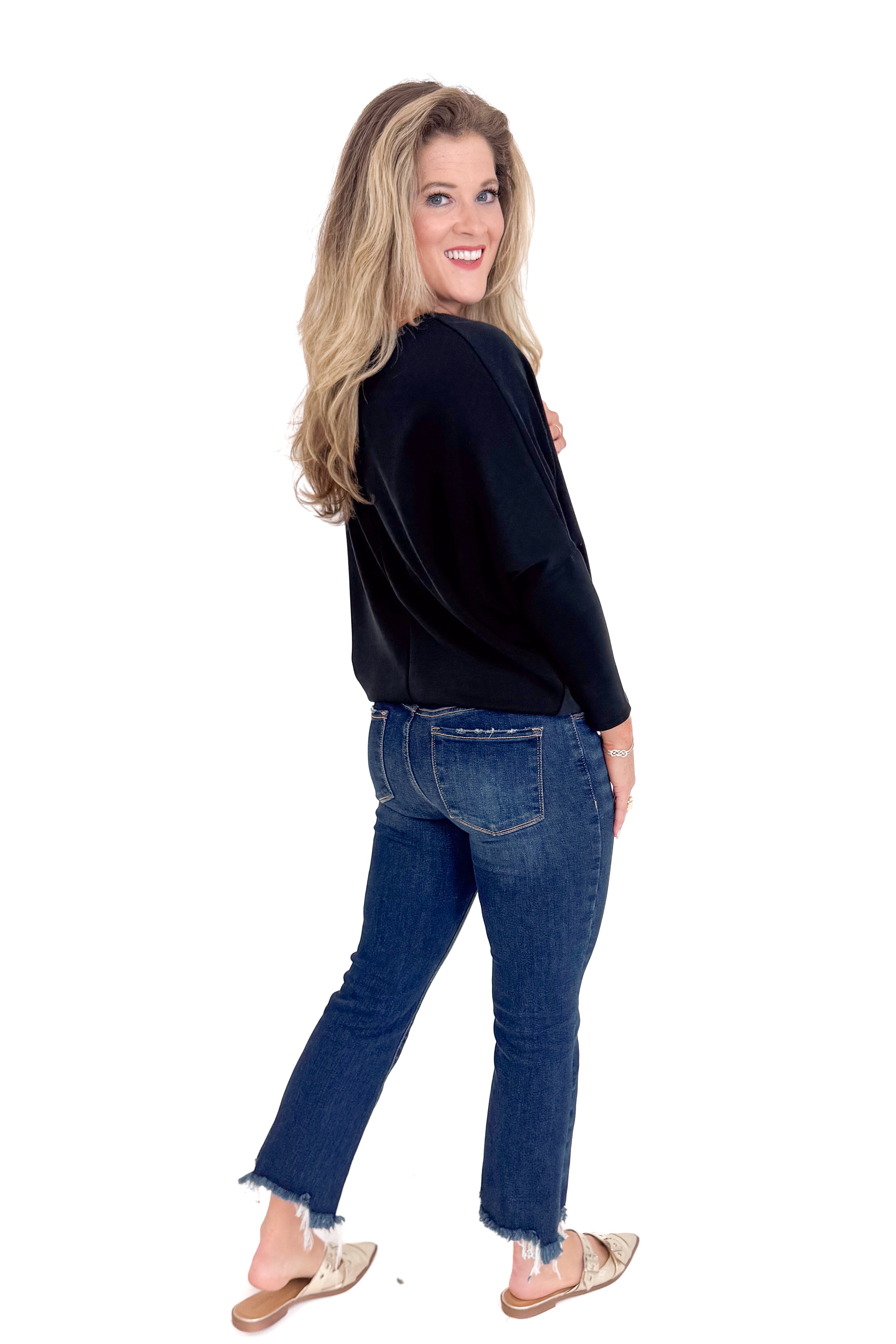 Woman wearing a black top and blue jeans on a white background