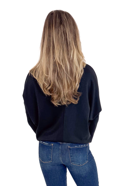 Person wearing a black sweater and blue jeans from behind on a white background