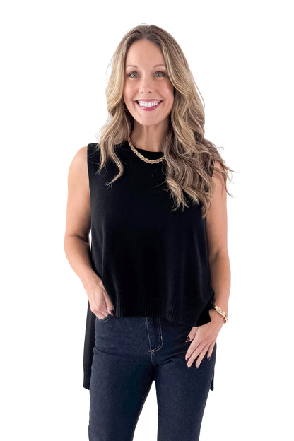 Front view of woman wearing black sweater with jeans against white studio background.