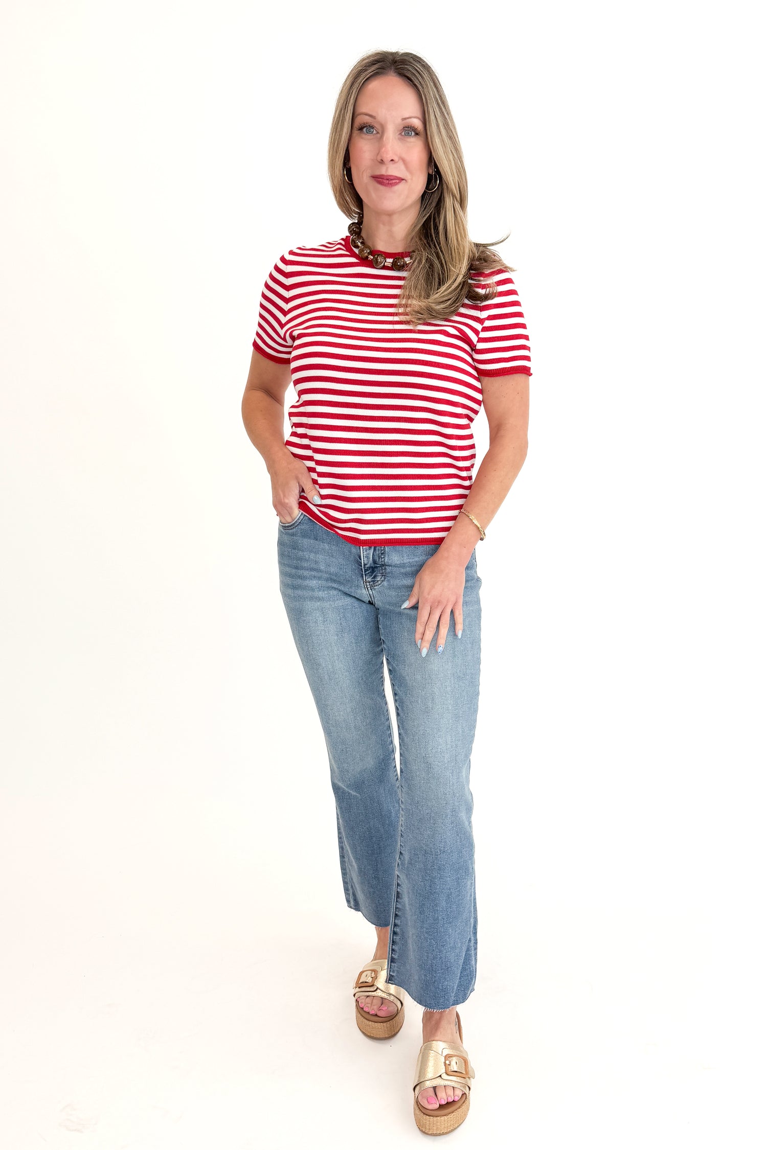 Front view of woman wearing Red &amp; White Striped Short Sleeve Sweater with jeans against white studio background.