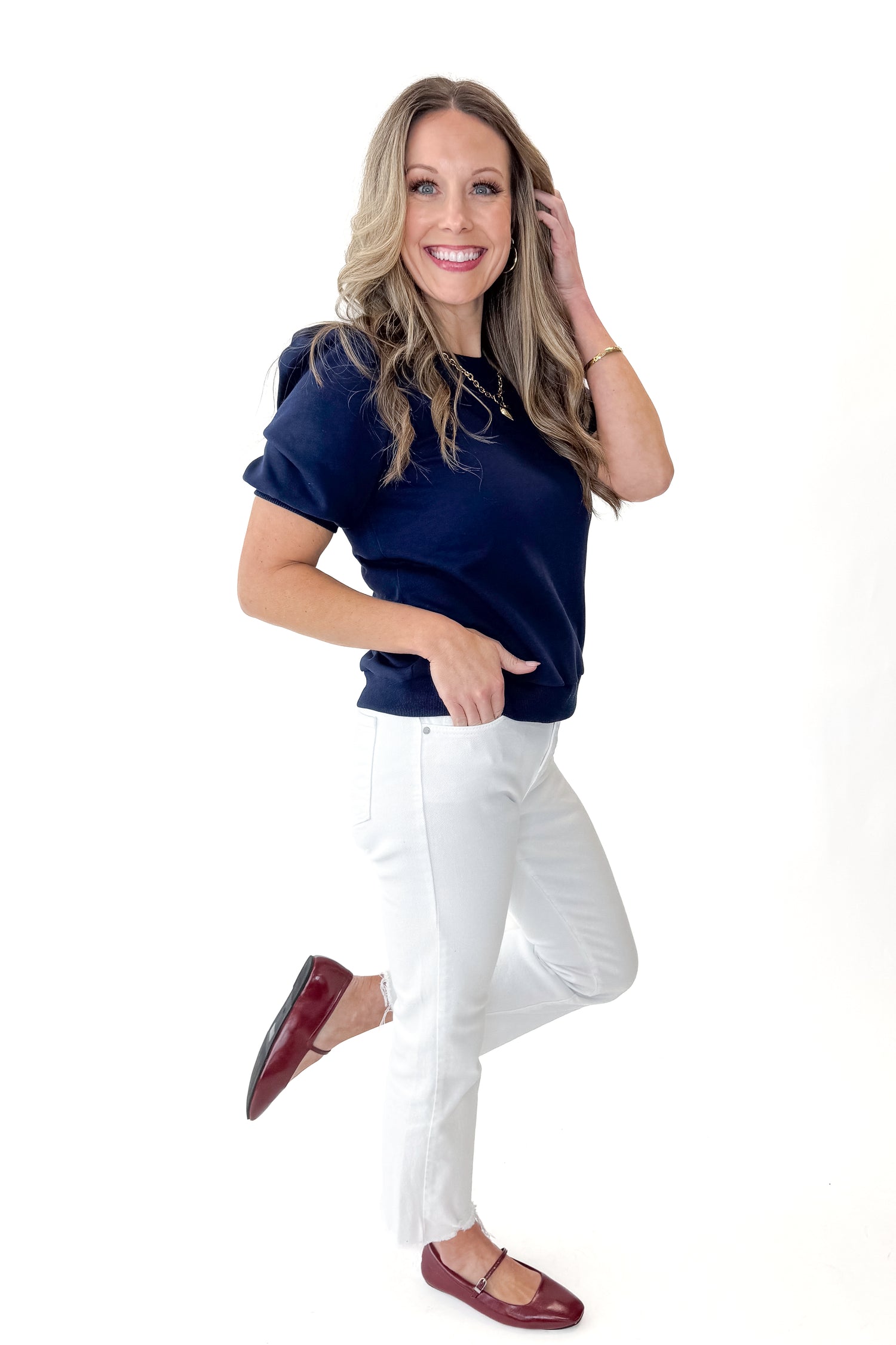 Side view of woman wearing Navy Short Sleeve Sweatshirt with jeans against white studio background.