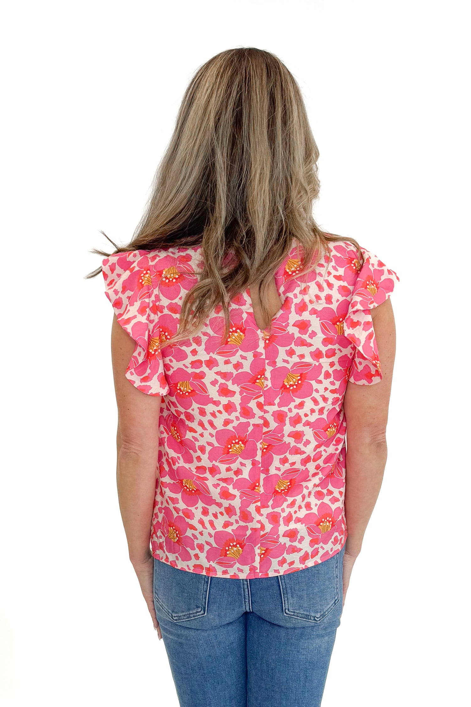 Back view of woman wearing Pink Floral Printed Ruffle Sleeve Top with jeans against white studio background.