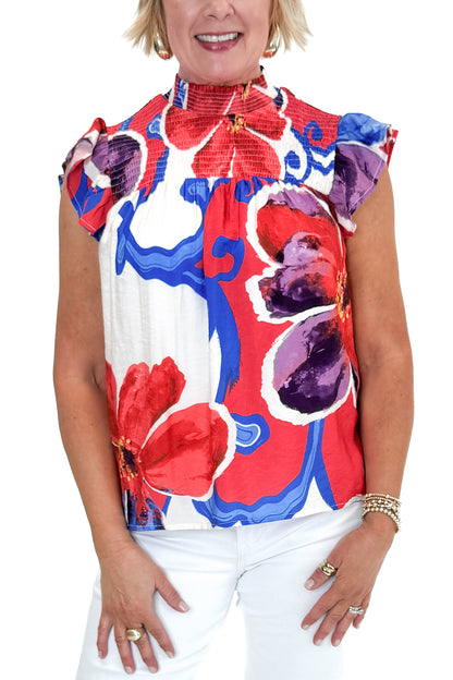 Front detail view of woman wearing Multi Floral Smocked Detail Top with jeans against white studio background.