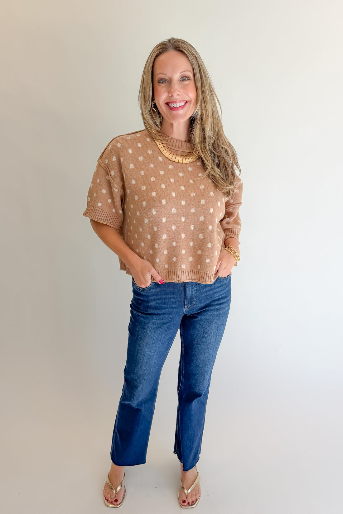 Front view of woman wearing Swagger Boutique’s Camel Polka Dot Short Sleeve Sweater by Entro with jeans against white studio background.