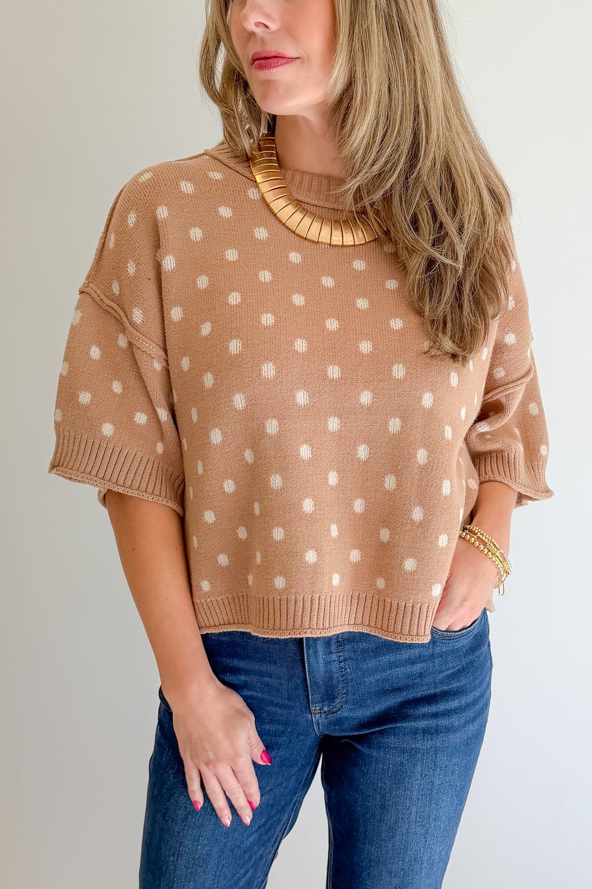 Front detail view of woman wearing Swagger Boutique’s Camel Polka Dot Short Sleeve Sweater by Entro with jeans against white studio background.