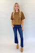 Front view of woman wearing Swagger Boutique’s Camel Suede Horsebit Pocket Top by Entro with jeans against white studio background.