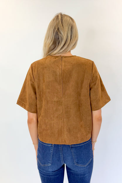 Back view of woman wearing Swagger Boutique’s Camel Suede Horsebit Pocket Top by Entro with jeans against white studio background.