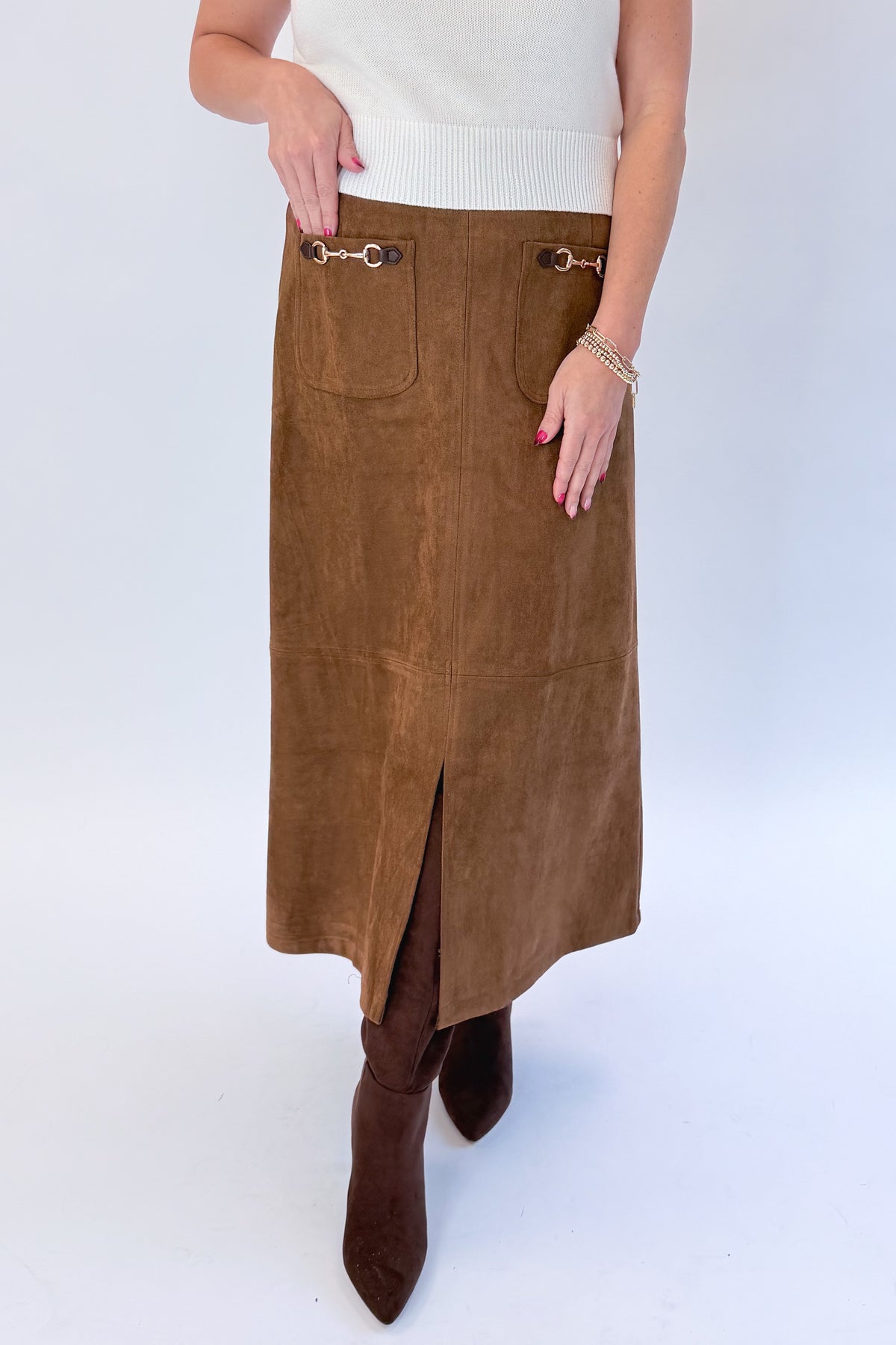 Front view of woman wearing Swagger Boutique’s White Cap Sleeve Sweater by PINCH with Camel Suede Midi Skirt With Pockets by Entro against white studio background.