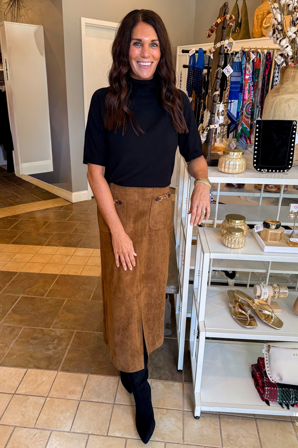 Front view of woman wearing Swagger Boutique’s black sweater with Camel Suede Midi Skirt With Pockets by Entro standing at the store.