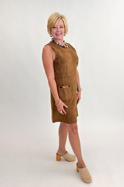 Side view of woman wearing Swagger Boutique’s Camel Suede Mini Dress With Pockets by Entro with clogs against white studio background.