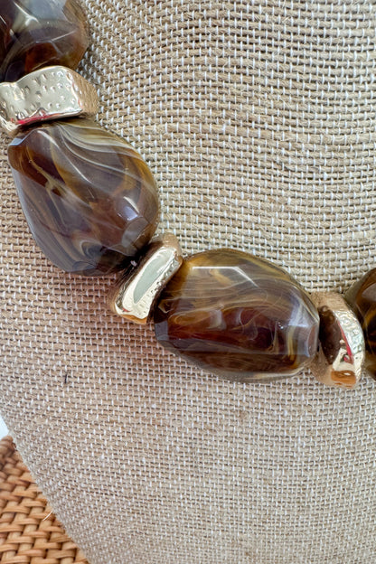 Chunky Brown Beaded Necklace with Gold Accents on a beige bust