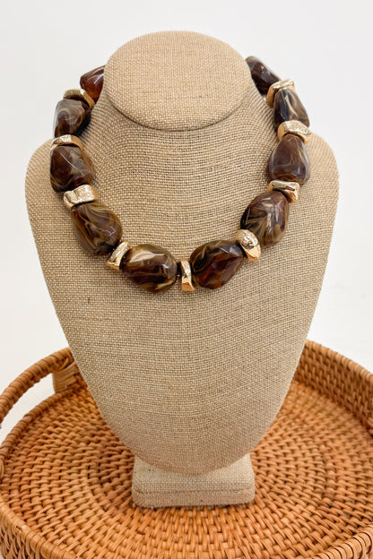 Chunky Brown Beaded Necklace with Gold Accents on a beige bust