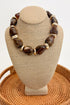 Chunky Brown Beaded Necklace with Gold Accents on a beige bust