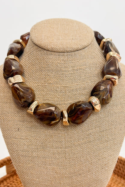 Chunky Brown Beaded Necklace with Gold Accents on a beige bust