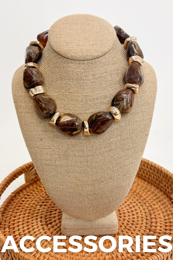 front view of brown and gold necklace on tan bust that says accessories at the bottom 