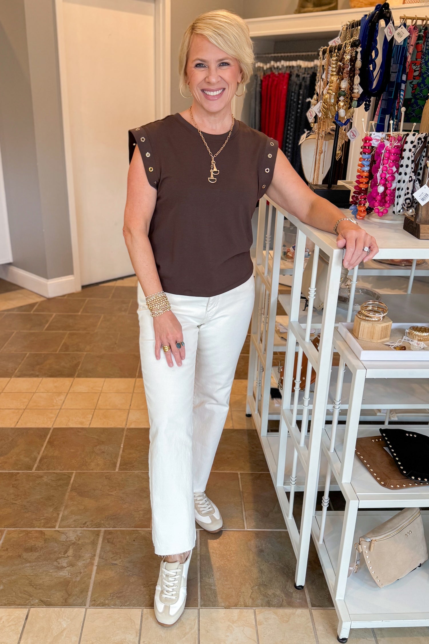 Front view of woman wearing Swagger Boutique’s Dark Chocolate Camino Grommet Top by Z Supply with jeans at the store.