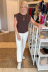 Front view of woman wearing Swagger Boutique’s Dark Chocolate Camino Grommet Top by Z Supply with jeans at the store.