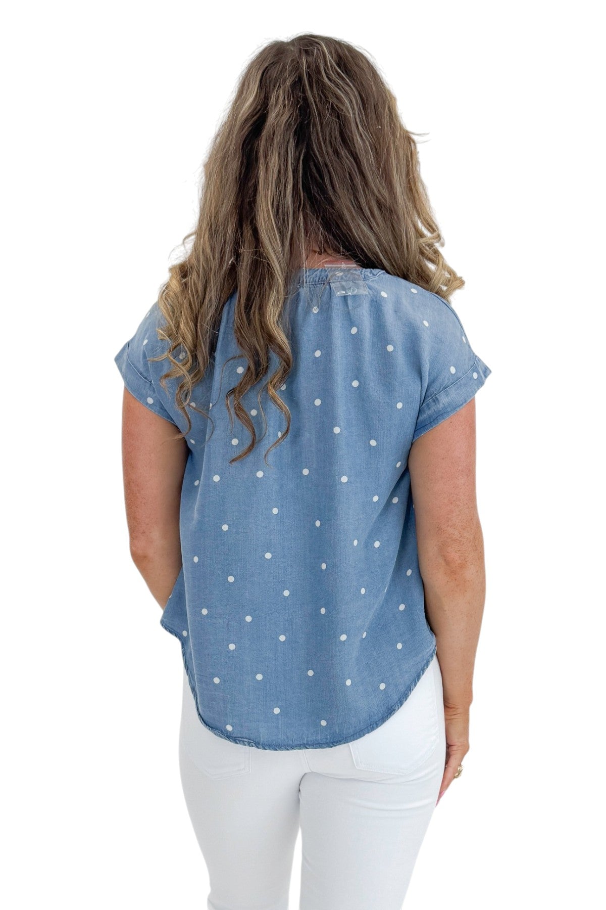 Back view of woman wearing Swagger Boutique’s Chambray Polka Dot Short Sleeve Top with jeans against white studio background.